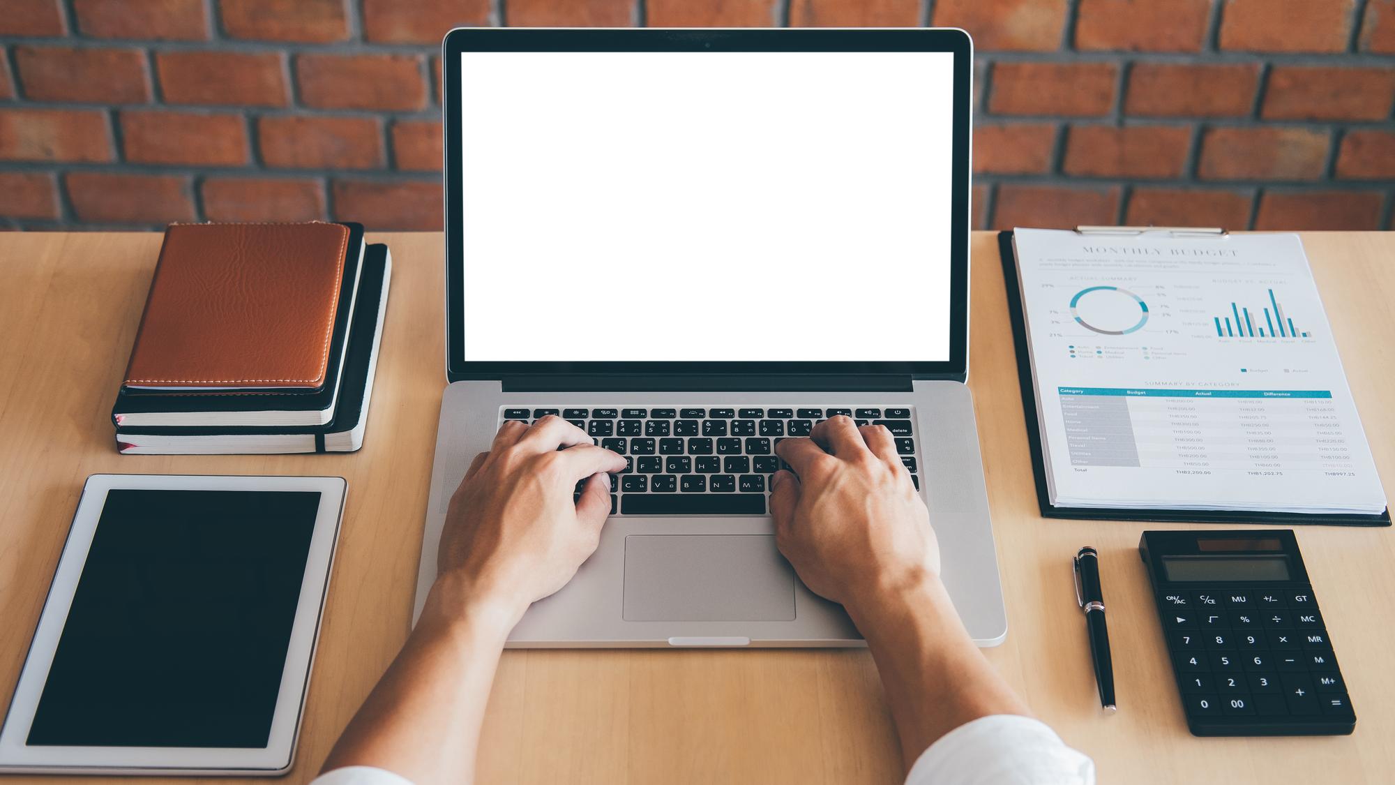 Hand zeigt auf Finanzplan auf Laptop